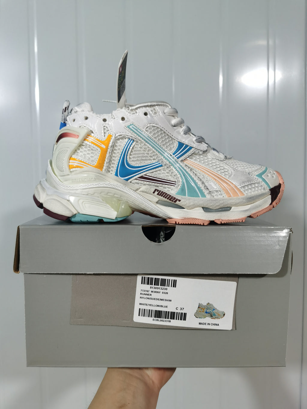 Balenciaga Runner sneaker in white with yellow, blue, teal, and burgundy accents displayed on its labeled shoe box.