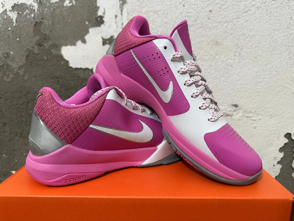 Two pink and white Nike basketball shoes displayed together, showing the side panels, Swoosh, and pink-and-gray soles.