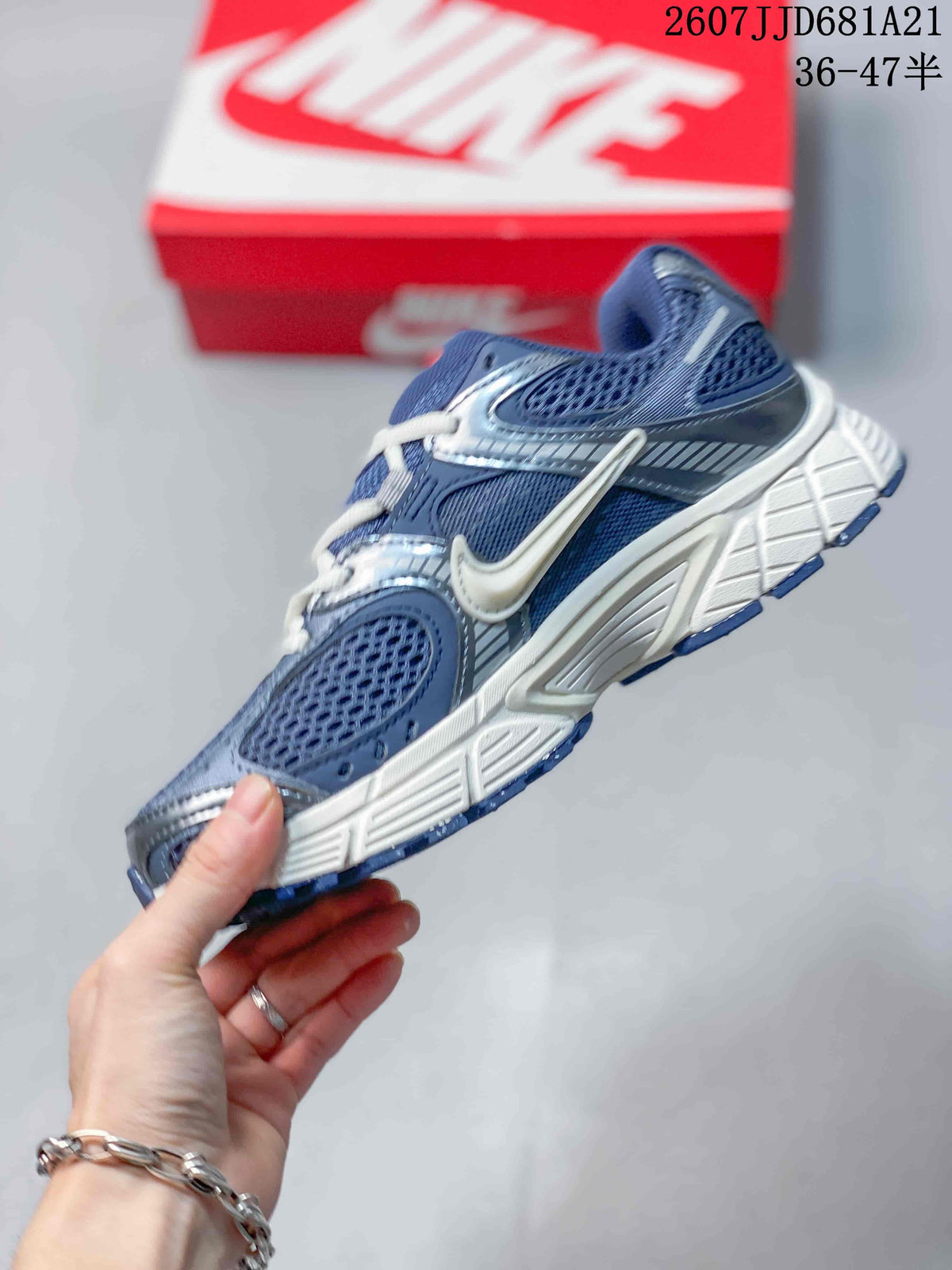 Side profile of a blue and white Nike V5 RNR sneaker showing layered panels, mesh-style sections and a sculpted white midsole.