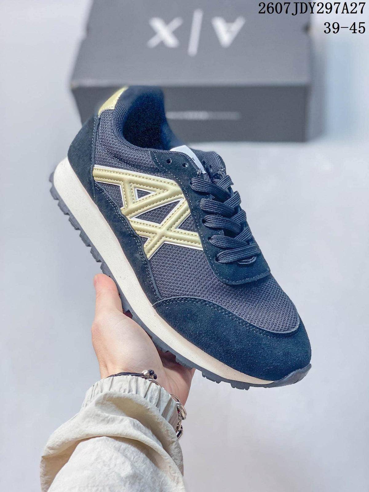 Three-quarter side view highlighting the navy upper, gold side logo detail, light-colored midsole, and lace-up construction.