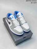 Pair of low-top Jordan sneakers on a shoebox, showing white, grey, blue and black panels with elephant-print detailing.
