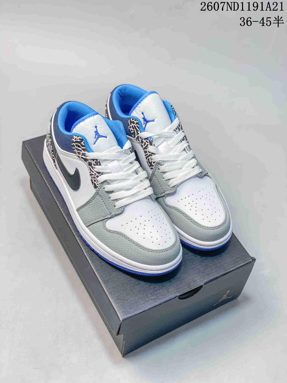 Pair of low-top Jordan sneakers on a shoebox, showing white, grey, blue and black panels with elephant-print detailing.