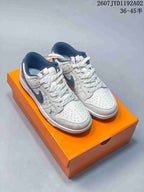 Pair of white and navy monogram-style low-top sneakers on an orange box
