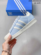 Side view highlighting the light blue upper, three white side stripes, white midsole, and low-top silhouette.
