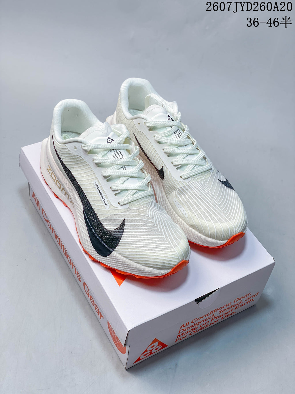 Pair of off-white Nike ACG Ultrafly Trail sneakers with black branding and orange outsoles displayed on a shoe box.