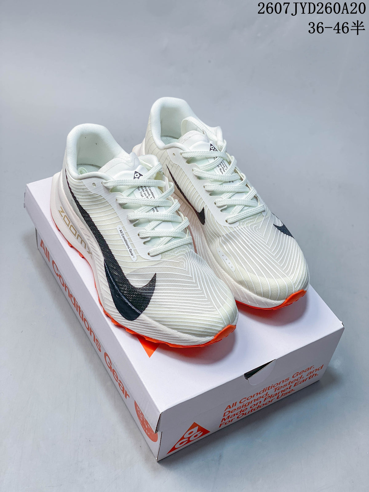 Pair of off-white Nike ACG Ultrafly Trail sneakers with black branding and orange outsoles displayed on a shoe box.