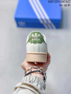 Rear view of the sneaker showing the green heel detail, white heel panel, and beige outsole.