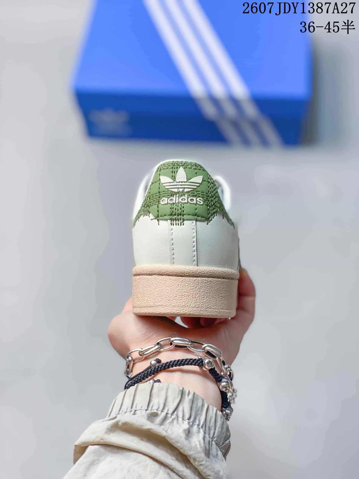 Rear view of the sneaker showing the green heel detail, white heel panel, and beige outsole.