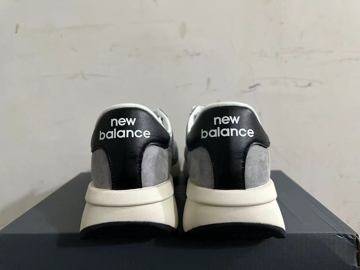 Rear view of gray and white New Balance U370 sneakers with black heel panels.