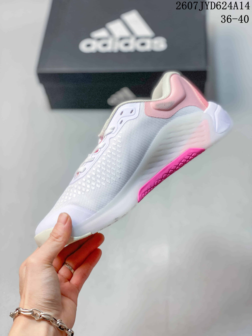 Side view showing the mesh upper, lace-up construction, gray adidas stripes and pink outsole detail.