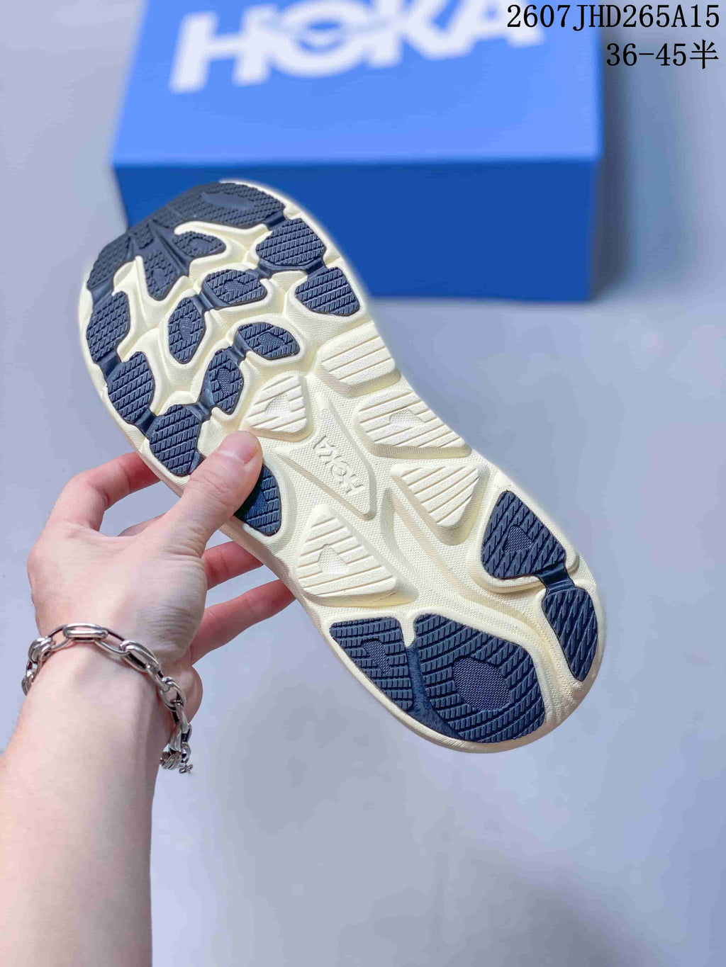 Close view of the patterned cream and dark outsole of a HOKA Clifton 10 sneaker.