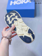 Close view of the patterned cream and dark outsole of a HOKA Clifton 10 sneaker.