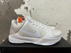 Side view of a silver and white Nike Kobe basketball shoe with a low-cut profile and Zoom-marked midsole.