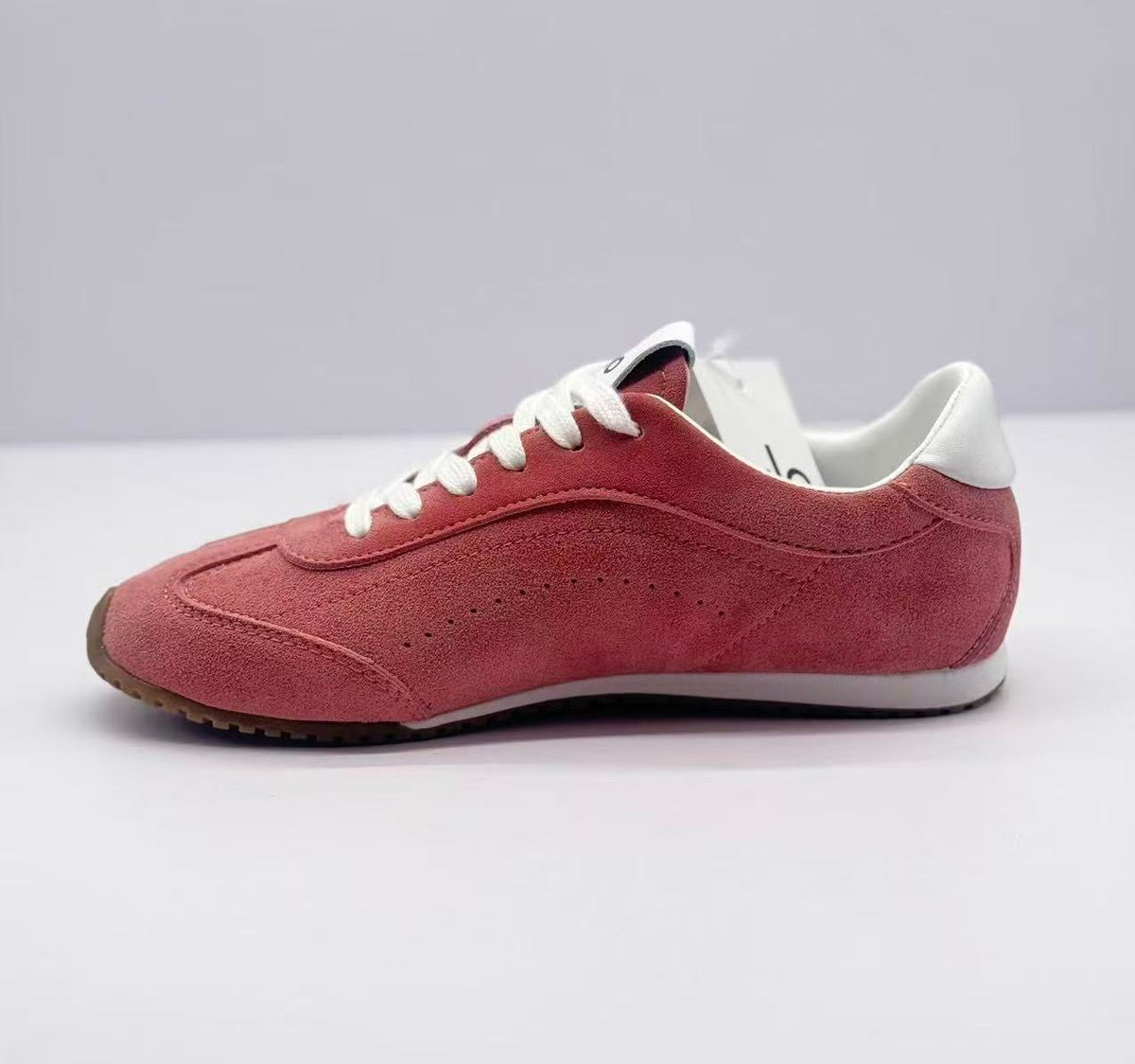 Opposite side view of the pink low-top sneakers with white collar and heel accents.