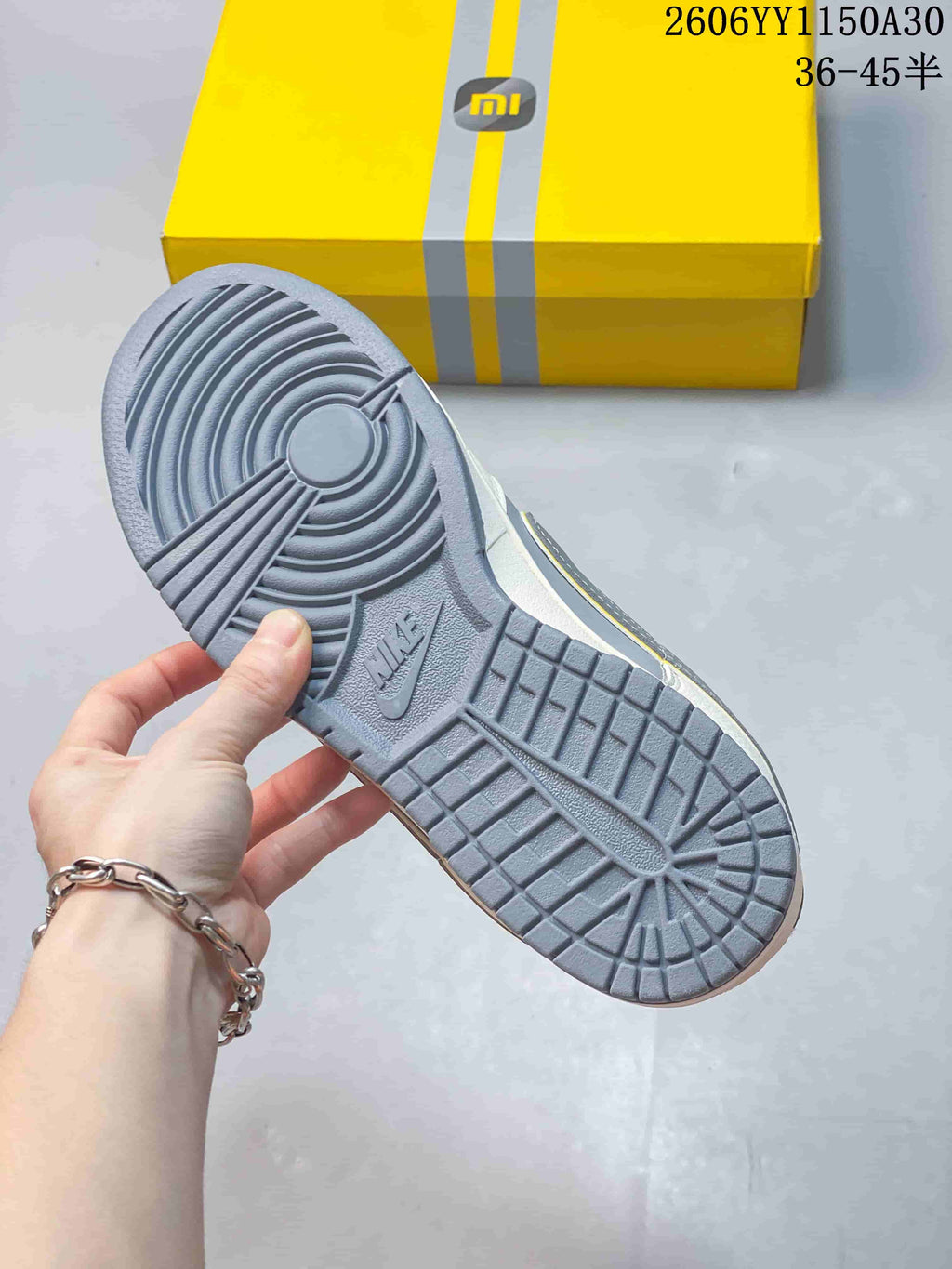 Grey outsole of a Nike SB Dunk Low sneaker with a yellow box in the background