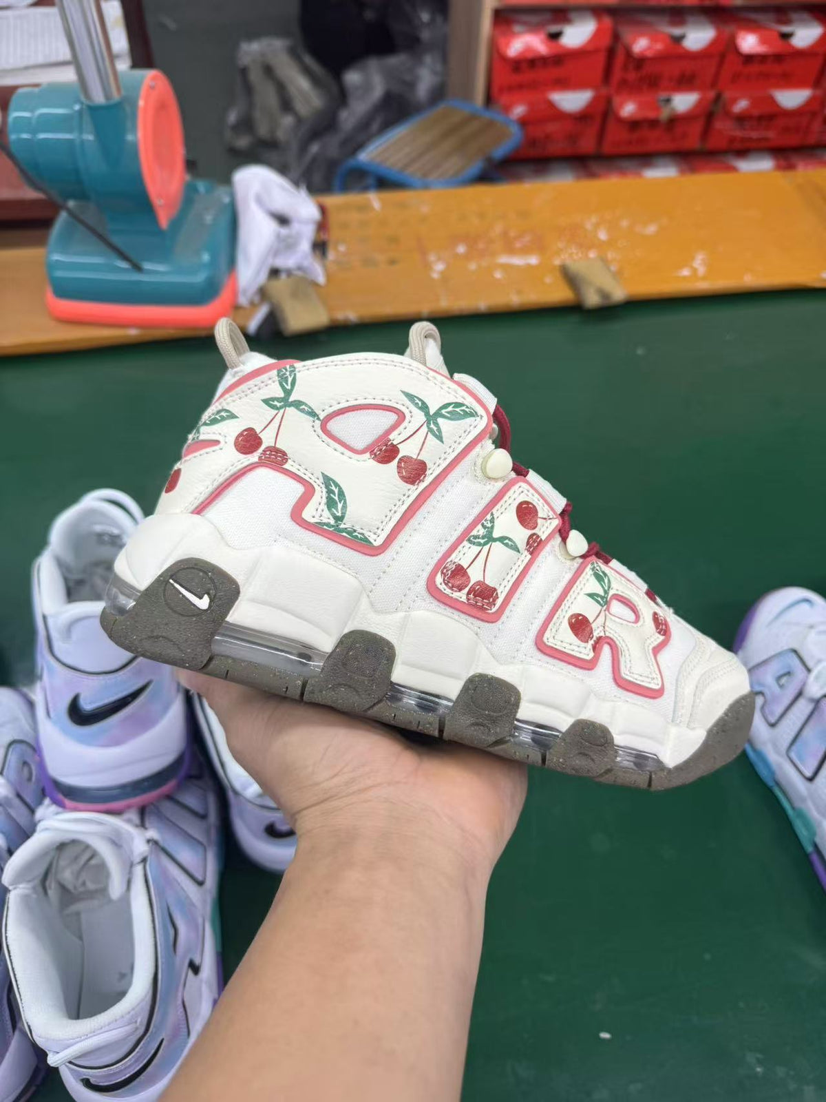 Hand-held view of the cherry-print sneaker in a workshop setting
