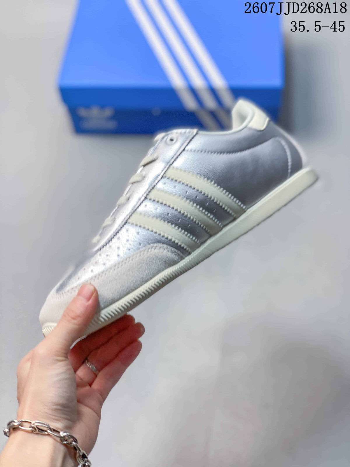 Side profile of the silver and white low-top sneaker showing its layered panels, side stripes, and low rubber sole.