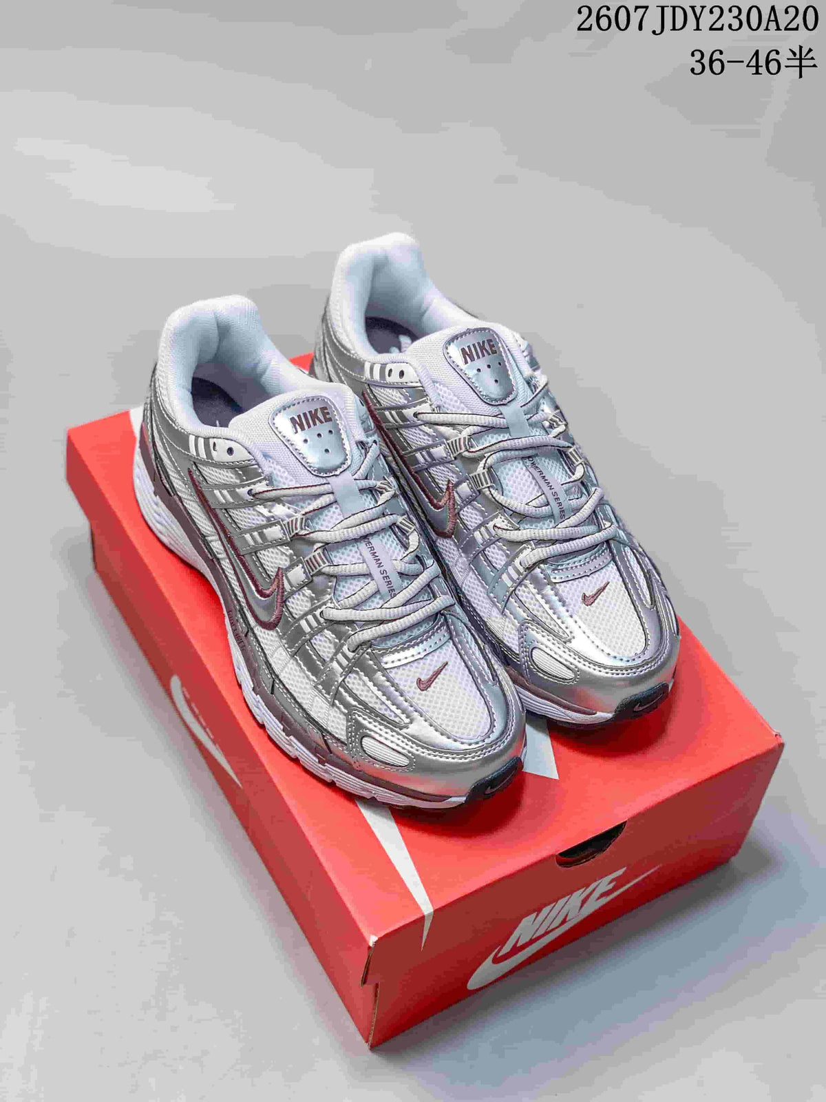 Pair of silver and white Nike P-6000 sneakers displayed on a red shoebox.