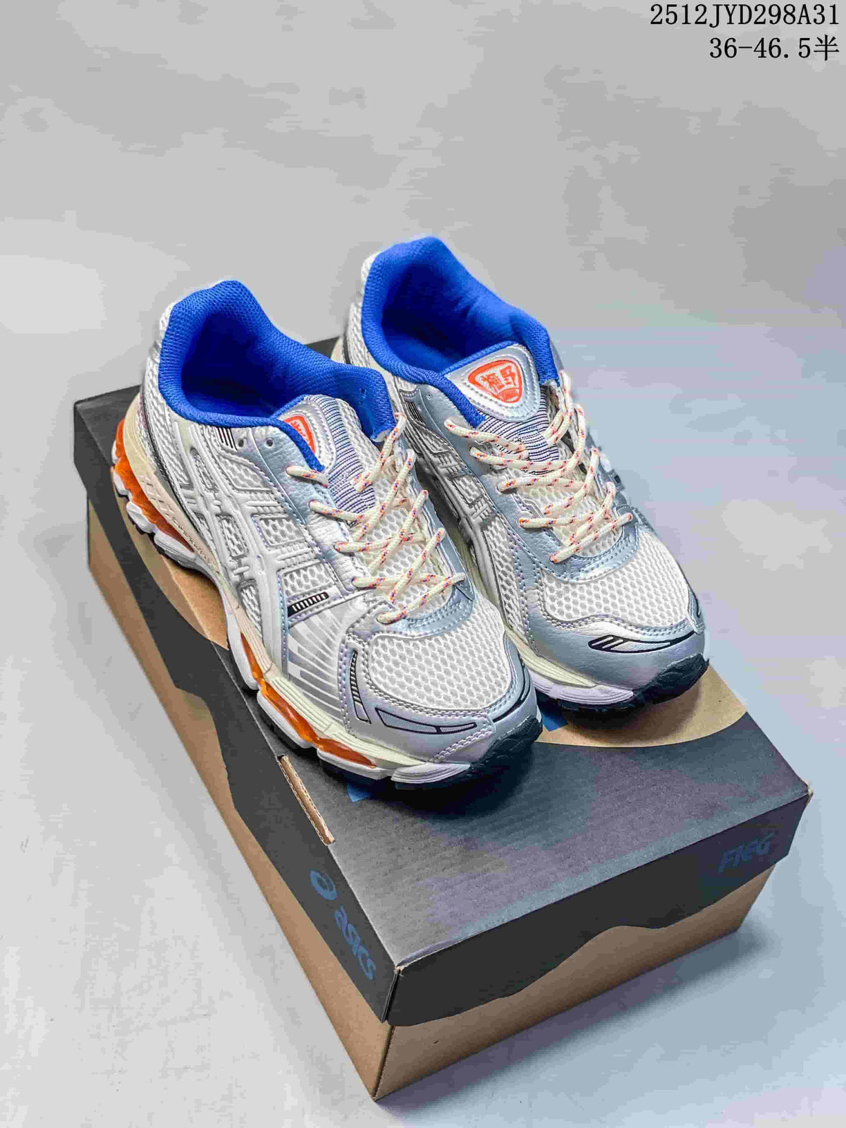 Silver and white ASICS Gel-Kayano 12.1 shoes with blue and orange accents, shown on a shoebox