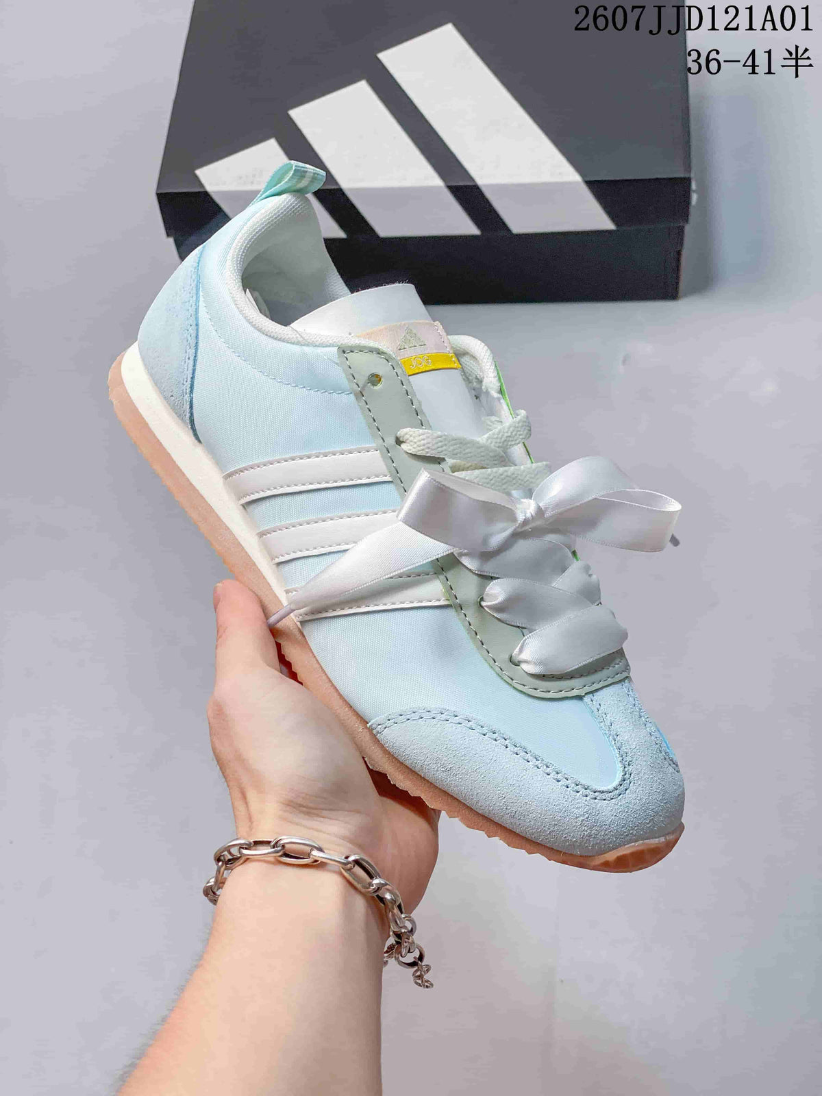 Angled view of a pale blue and white adidas JOG 2.0 sneaker with gum-colored outsole