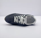 Top view of one carbon gray sneaker showing the lace arrangement, tongue branding, and white lining.