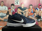 Side view of a dark Nike basketball shoe with a white Swoosh, patterned toe and collar, and white midsole