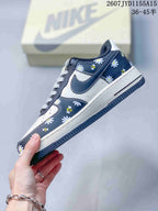 Side profile showing the navy Swoosh, white panels, floral and bee graphics, and layered sole.