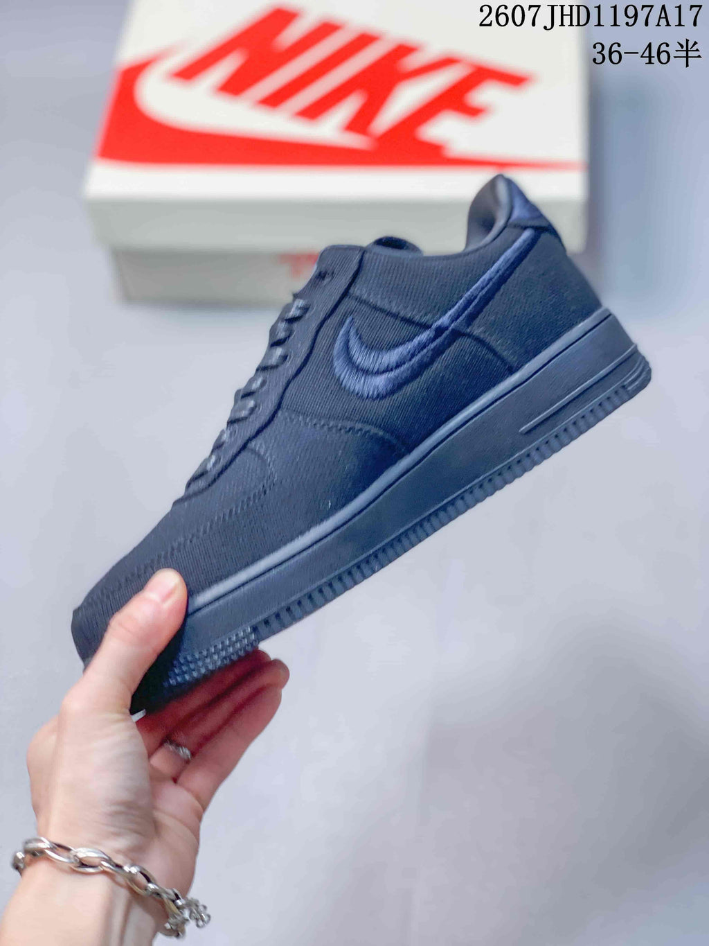 Side view of the black low-top sneaker showing the embroidered Swoosh, textured upper and matching rubber sole.