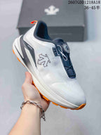 Angled side view showing the white and navy upper, BOA dial, Enerzite side marking, and orange outsole.