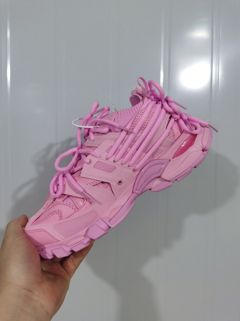 Close-up view of a pink Balenciaga Track sneaker showing its layered upper, multiple laces, mesh panels and chunky outsole.