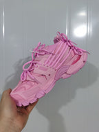 Close-up view of a pink Balenciaga Track sneaker showing its layered upper, multiple laces, mesh panels and chunky outsole.