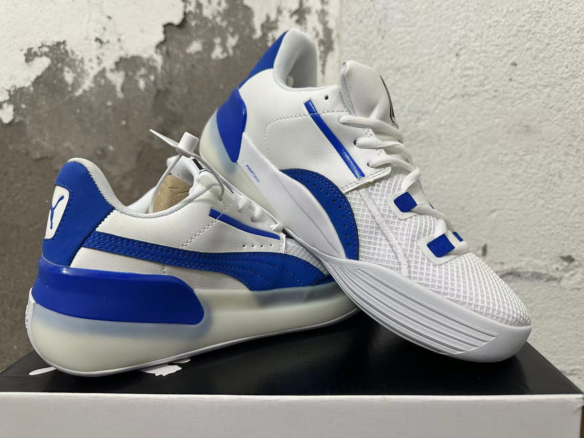 Angled view of white and blue Puma sneakers showing the mesh-look toe and side detailing.