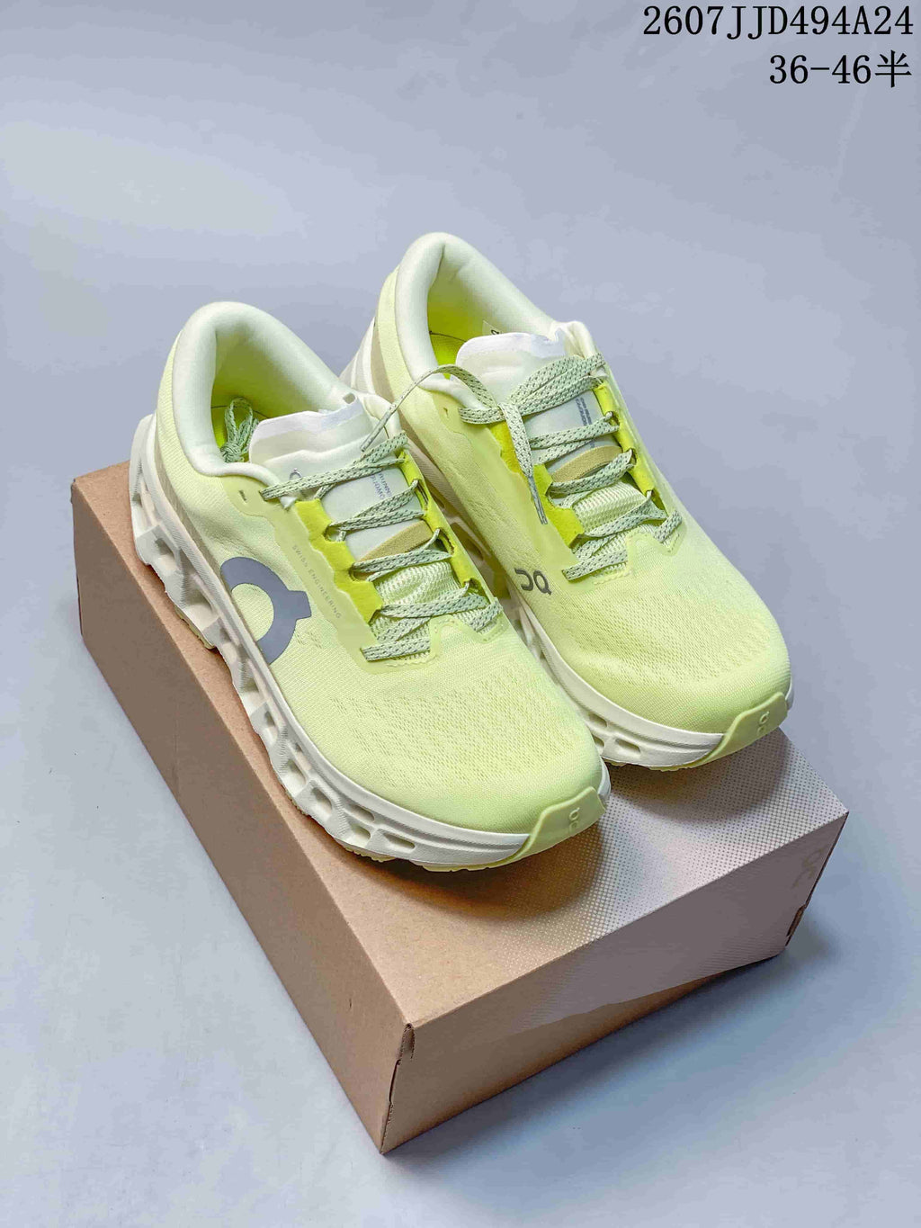 Pair of pale lime green and white On Cloudmonster 3 sneakers displayed on a shoebox.