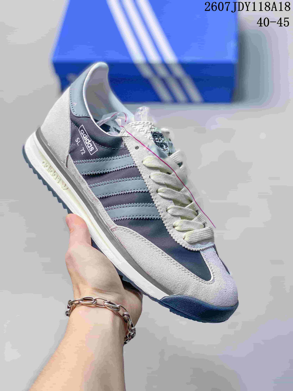 Gray, white and dark blue adidas SL 72 sneaker with a blue outsole and three-stripe branding.