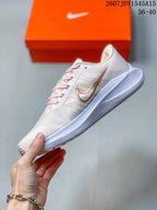 Side profile of the pale pink and white sneaker showing layered side branding and the low-top shape.