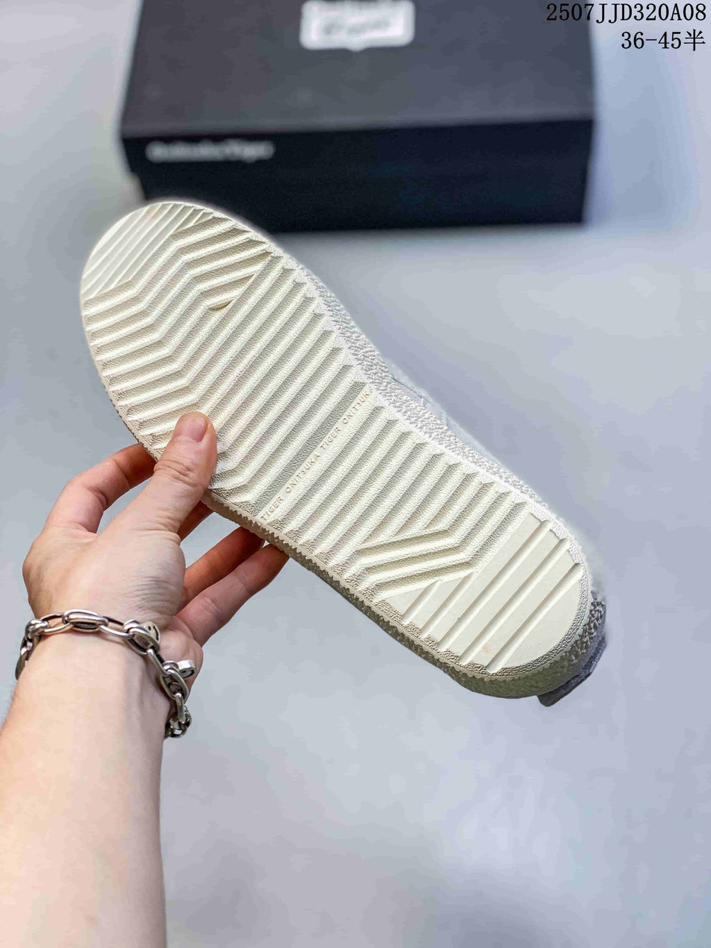 Close view of the patterned textured outsole on a light-colored ASICS sneaker, with a black shoebox in the background.