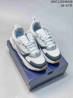 Pair of white Dior low-top sneakers with black and gray details displayed on a box.
