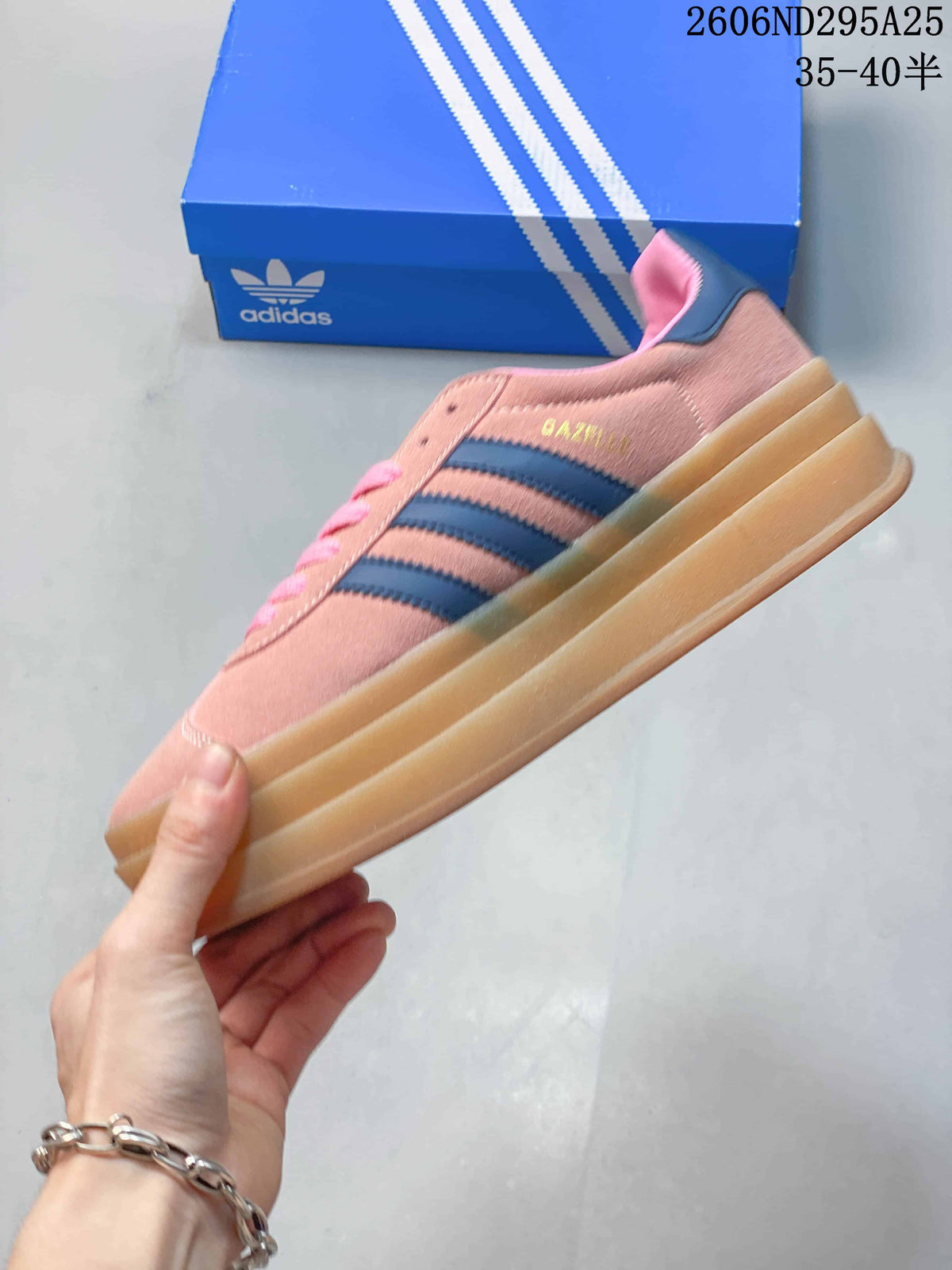 Side view showing the pink upper, navy three stripes, padded heel, and thick gum-colored platform sole.