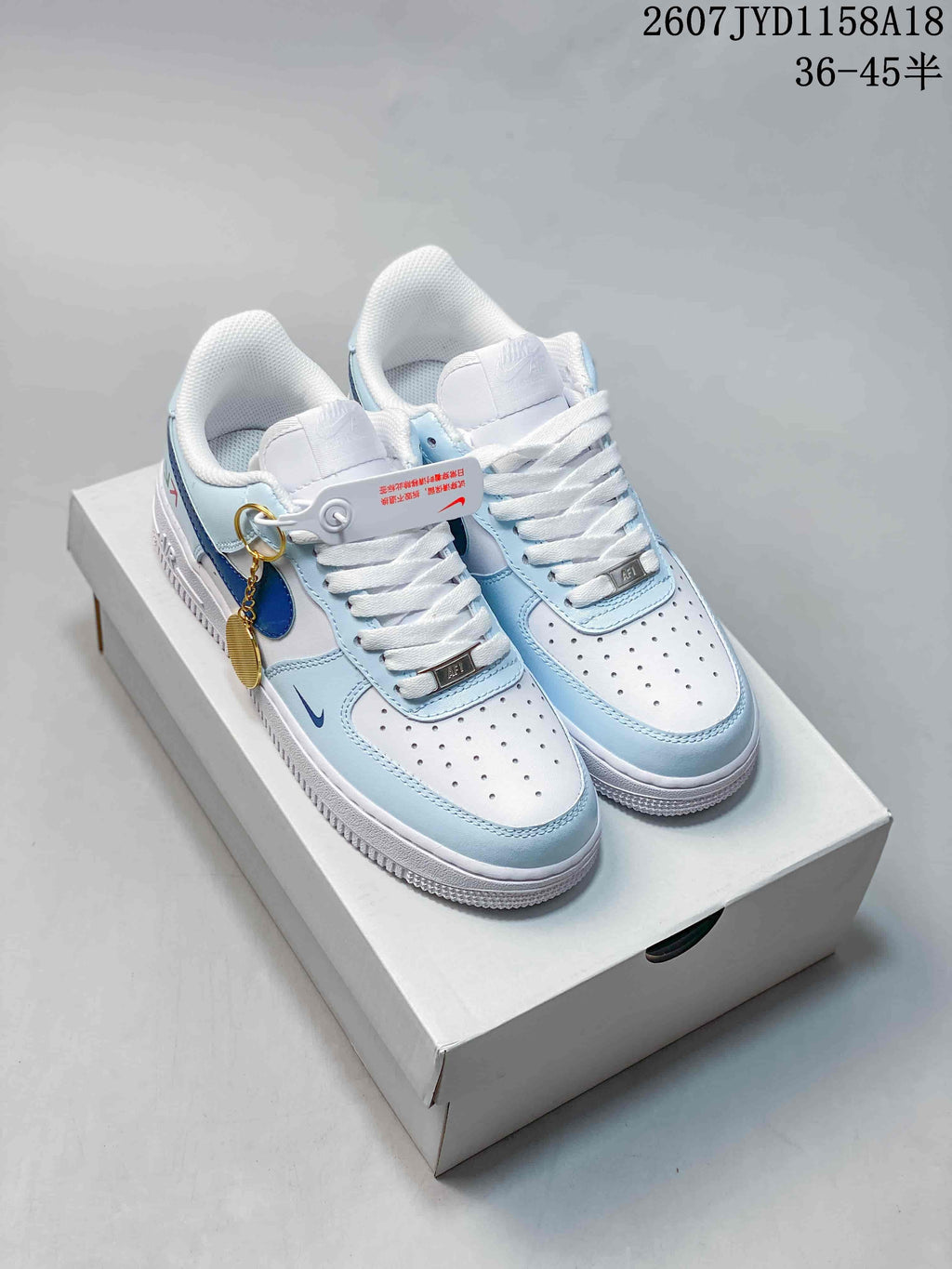 Pair of white and light blue Nike Air Force 1 '07 low-top sneakers displayed on a shoebox, with a visible size range marking of 36–45.