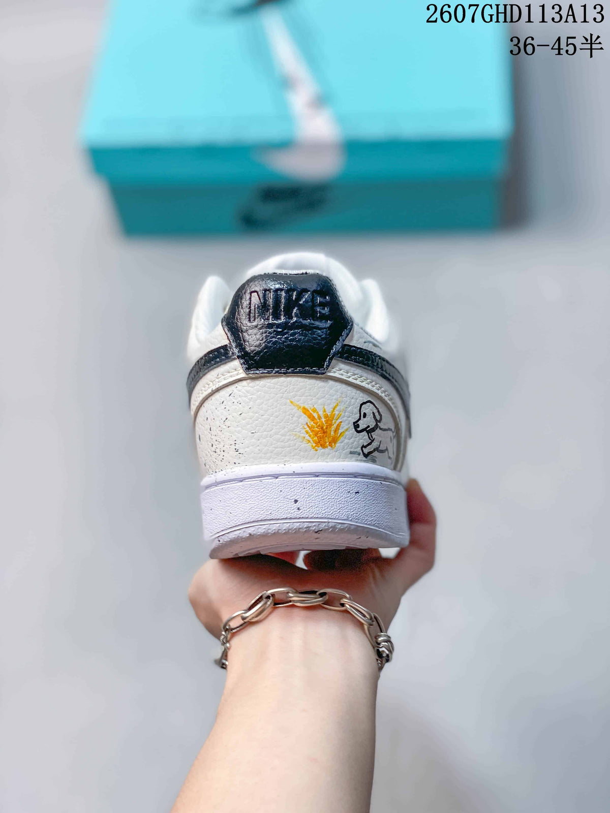 Rear view of the sneaker showing a black heel tab, white heel panel, and yellow and black illustrated details.