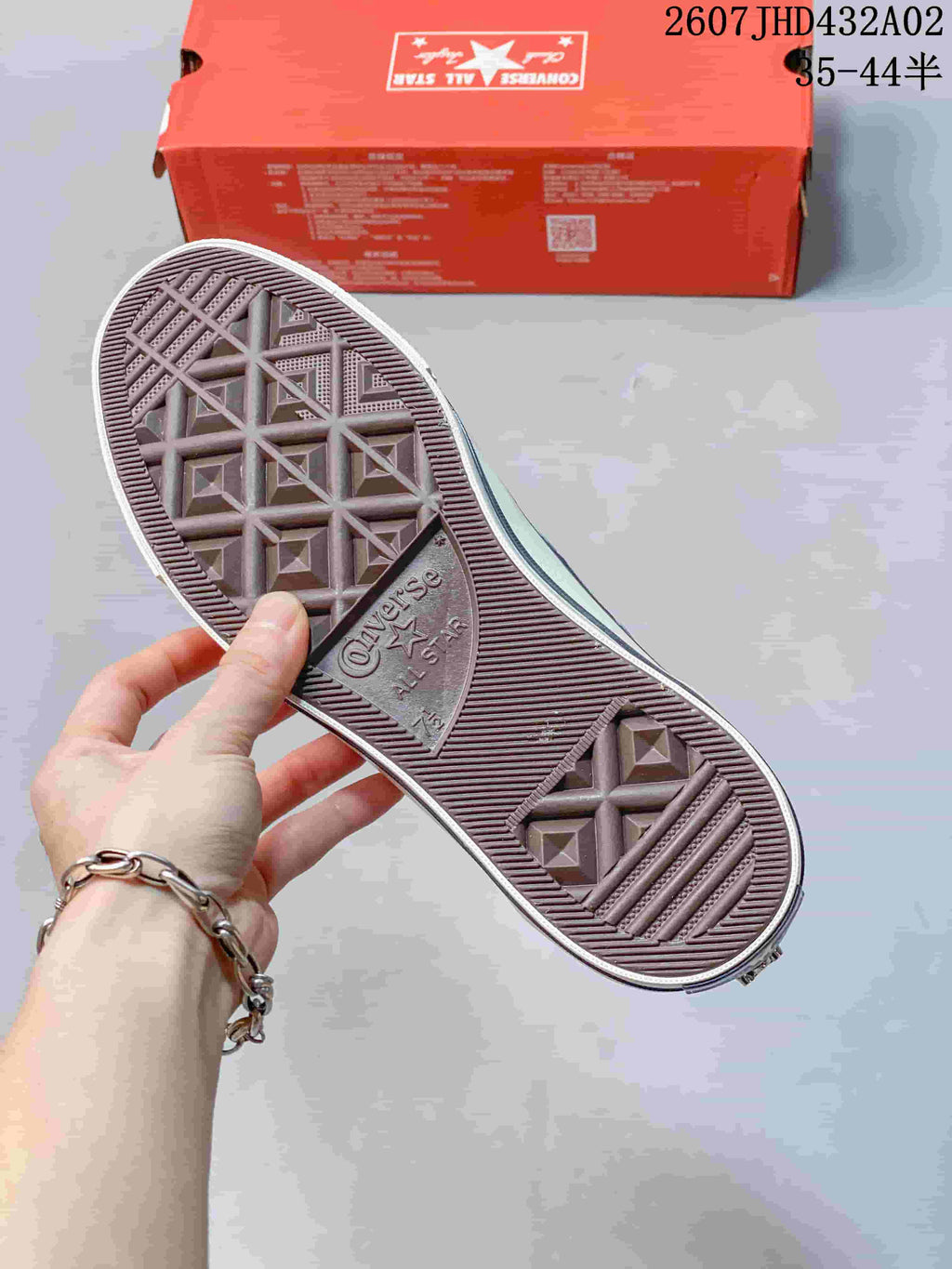 Close-up of the sneaker outsole with Converse All Star markings and a red shoe box in the background.