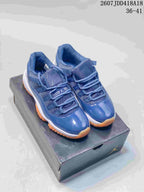 Pair of blue Jordan high-top sneakers displayed on a branded shoebox, showing the glossy toe panels and orange outsole.