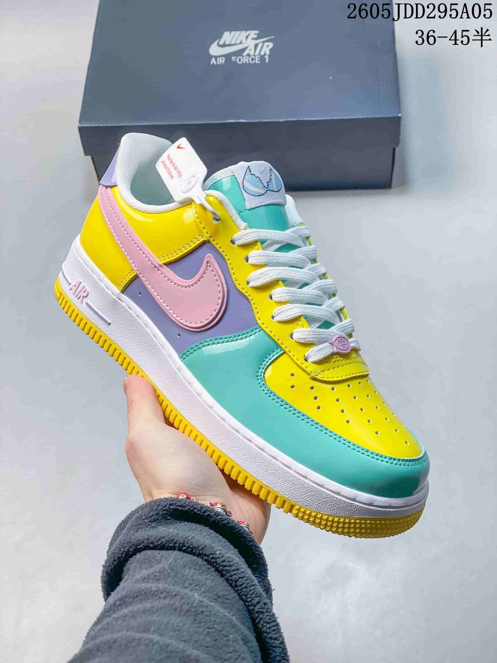 Angled side view of the multicolor Nike Air Force 1 sneaker showing the pink Swoosh, turquoise forefoot, yellow heel panel and white midsole.