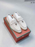 Pair of light beige lock-detail loafers displayed on a coral-colored box