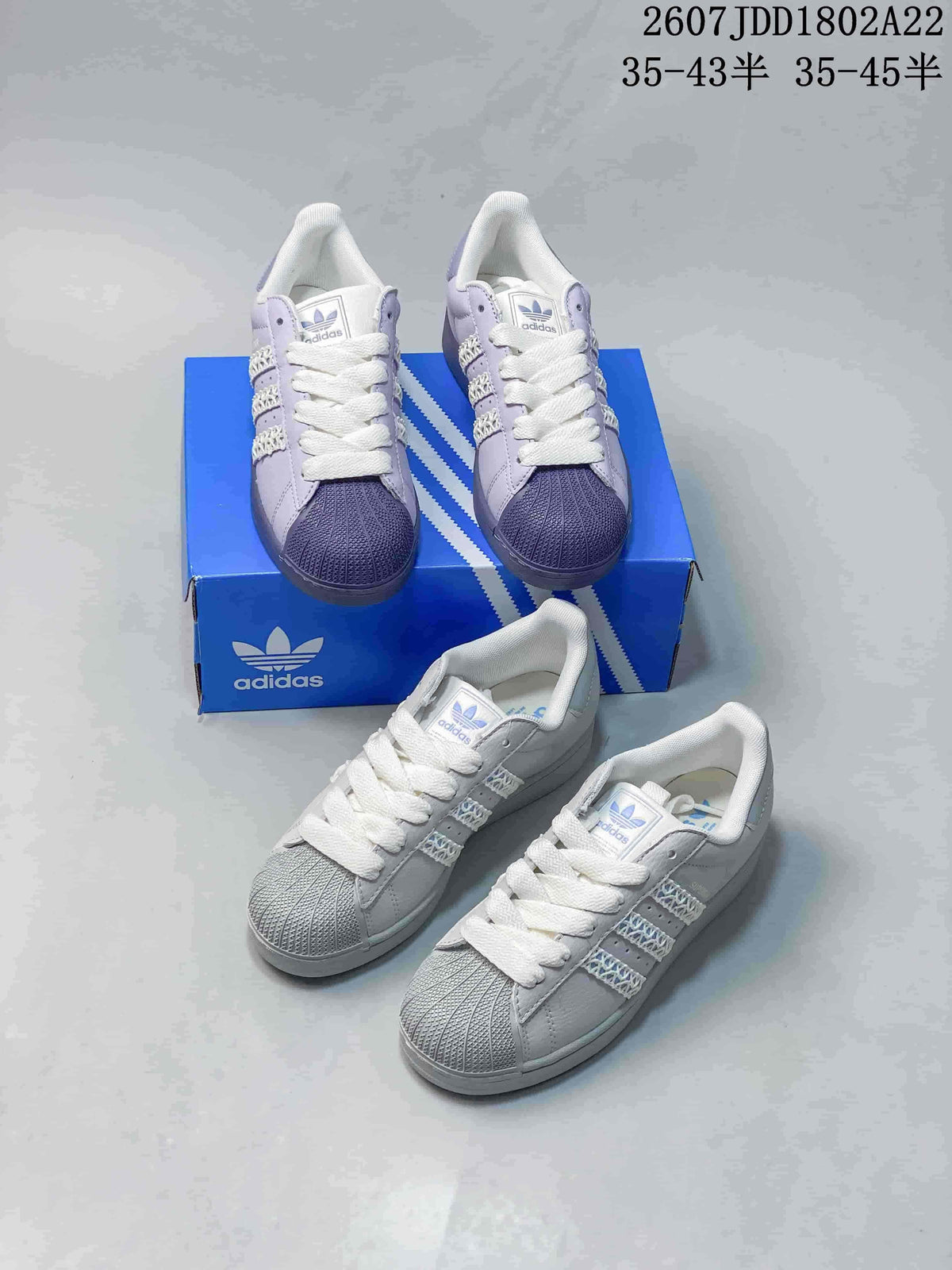 Multiple views of light-colored Adidas Superstar sneakers arranged around a blue Adidas shoe box.