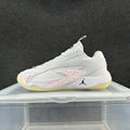 Side view of a white low-top sneaker with pink speckled accents, a black Jumpman-style logo, and a pale yellow outsole.