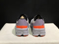 Rear view of gray On Cloud X sneakers with lavender-gray heel panels and orange bands.