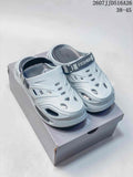 Light gray platform clog sandals shown from the front on a shoe box, with ventilation cutouts and an adjustable heel strap.