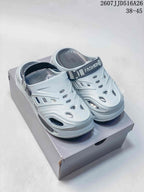 Light gray platform clog sandals shown from the front on a shoe box, with ventilation cutouts and an adjustable heel strap.