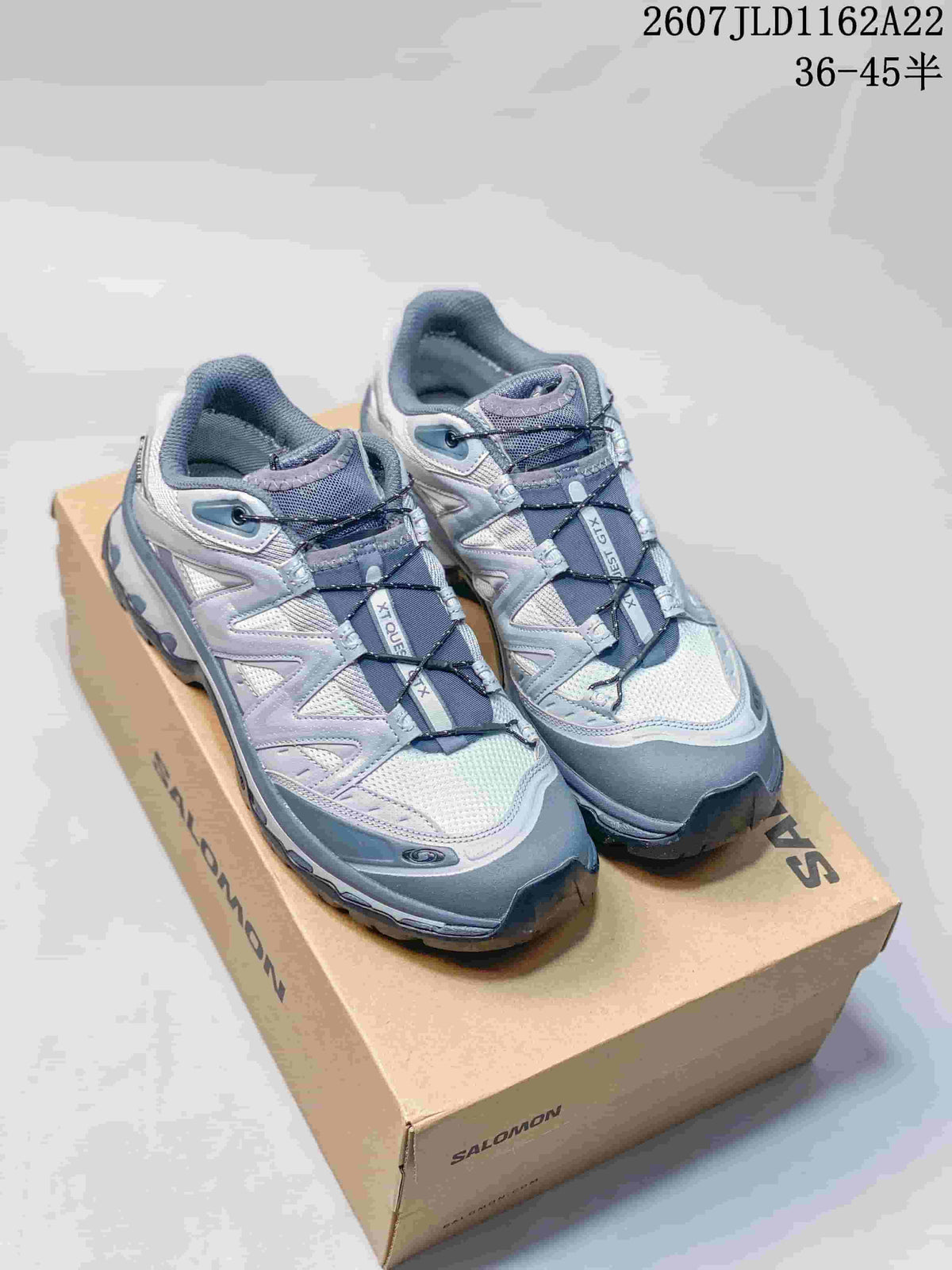 Pair of grey and silver Salomon XT-QUEST sneakers displayed on a Salomon shoe box.